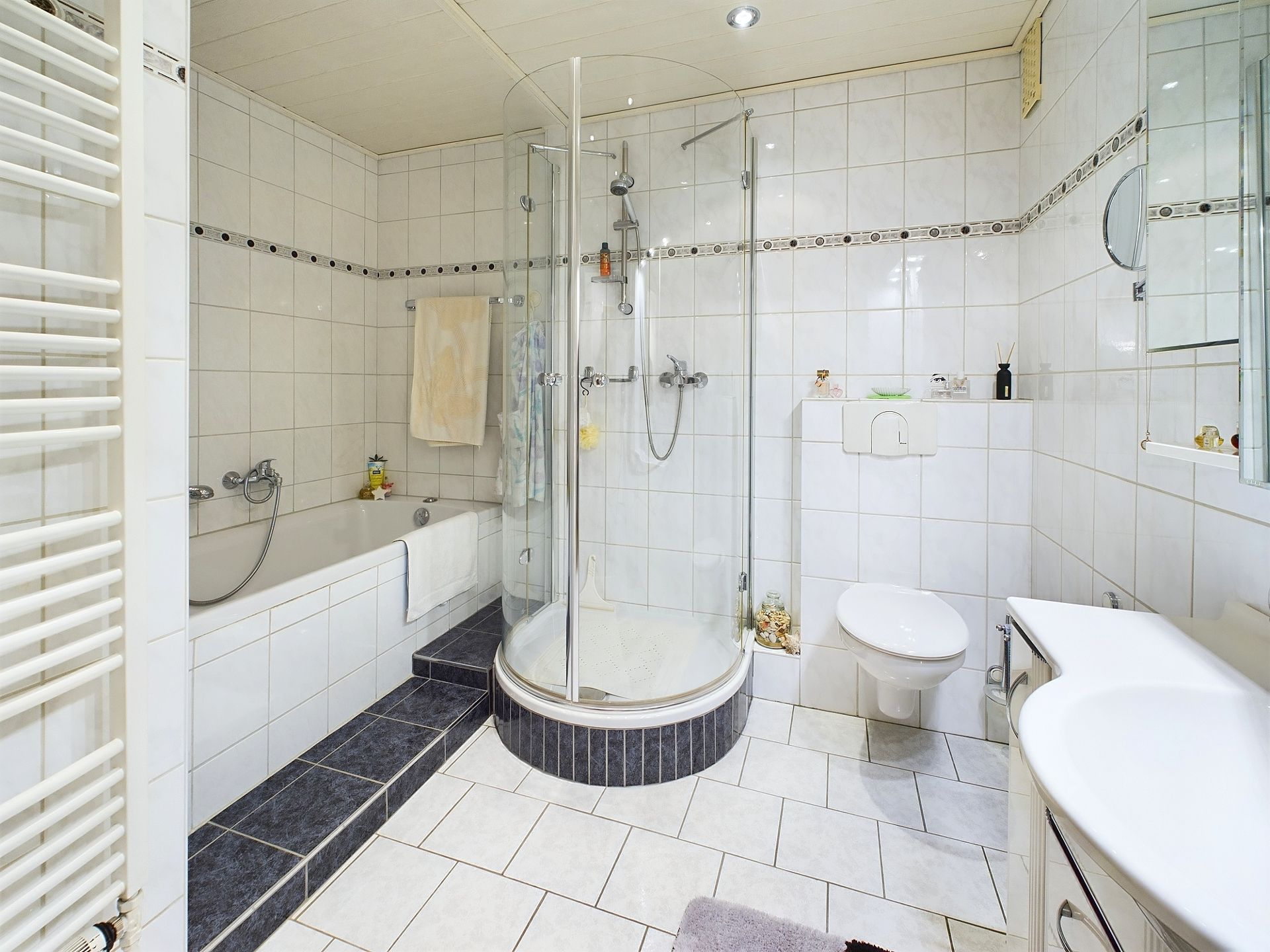 Modernes Badezimmer mit Badewanne, runder Dusche, WC und Waschbecken.