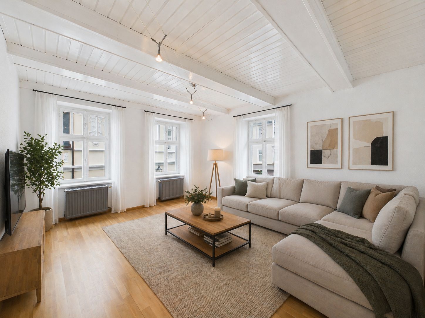 Helles Wohnzimmer mit Ecksofa, Couchtisch, Fernseher, Teppich und großen Fenstern.