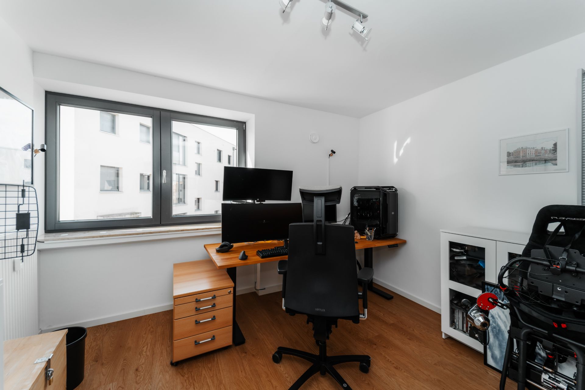 Helles Arbeitszimmer mit Schreibtisch, Bürostuhl, Computer und großem Fenster.