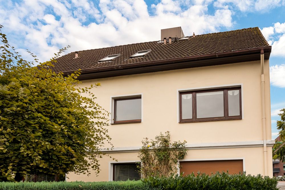 Außenansicht eines zweistöckigen Wohnhauses mit braunem Dach und großen Fenstern.