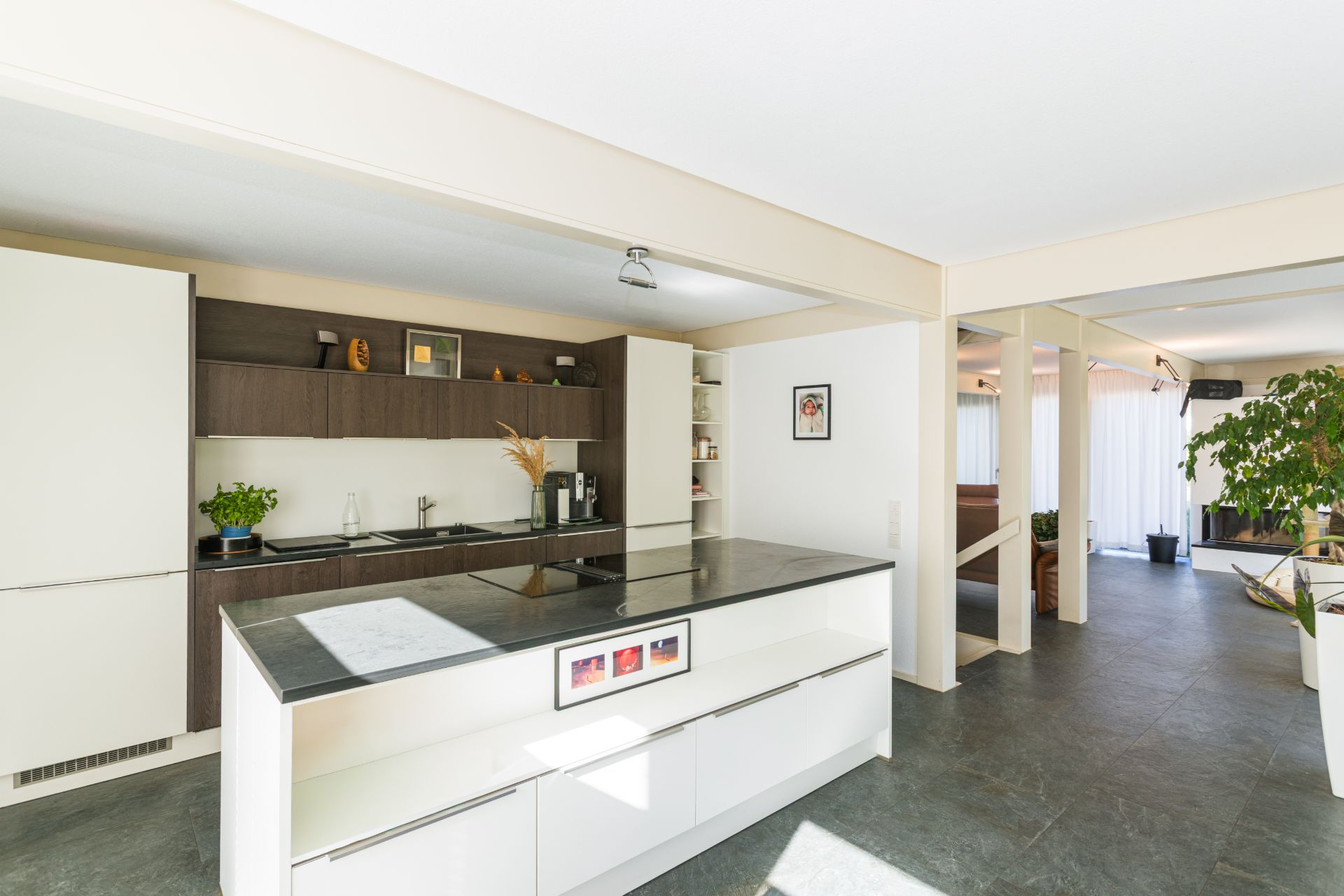 Moderne offene Küche mit Kochinsel und Blick ins helle Wohnzimmer.