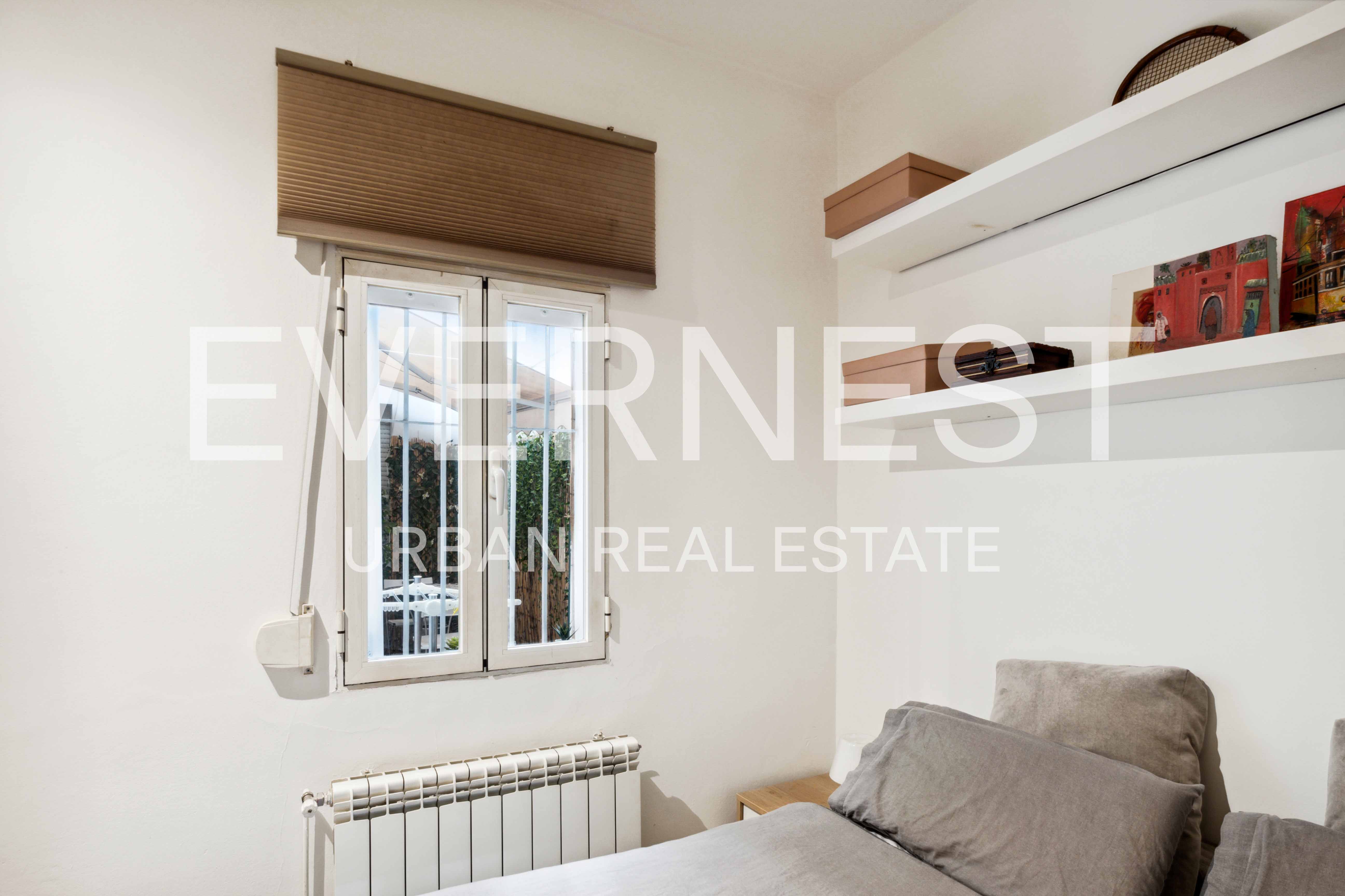 Kleines Schlafzimmer mit Fenster, Heizung, Bett und zwei Wandregalen mit Dekoration.