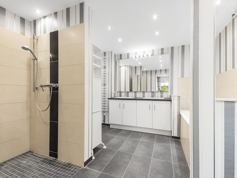 Modernes Badezimmer mit begehbarer Dusche, breitem Waschbecken und großem Spiegel.