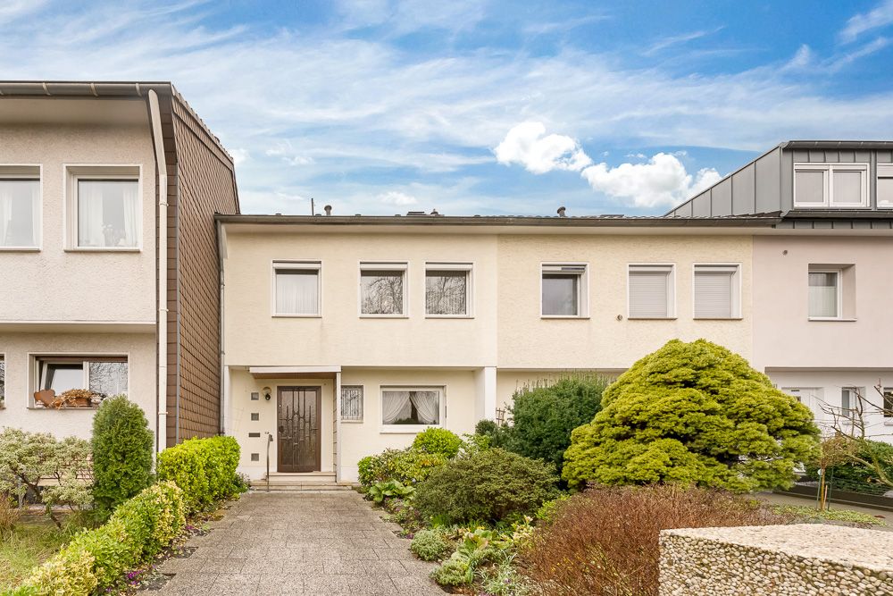 Zweistöckiges Reihenhaus mit Vorgarten und breitem Gehweg, umgeben von Nachbarhäusern.