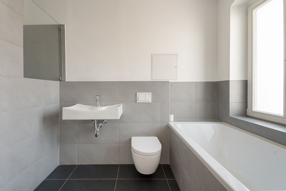 Modernes Badezimmer mit Waschbecken, Toilette, Badewanne und großem Fenster.