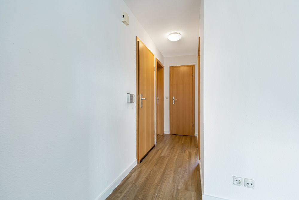 Heller Flur mit Holzboden und drei geschlossenen Holztüren.