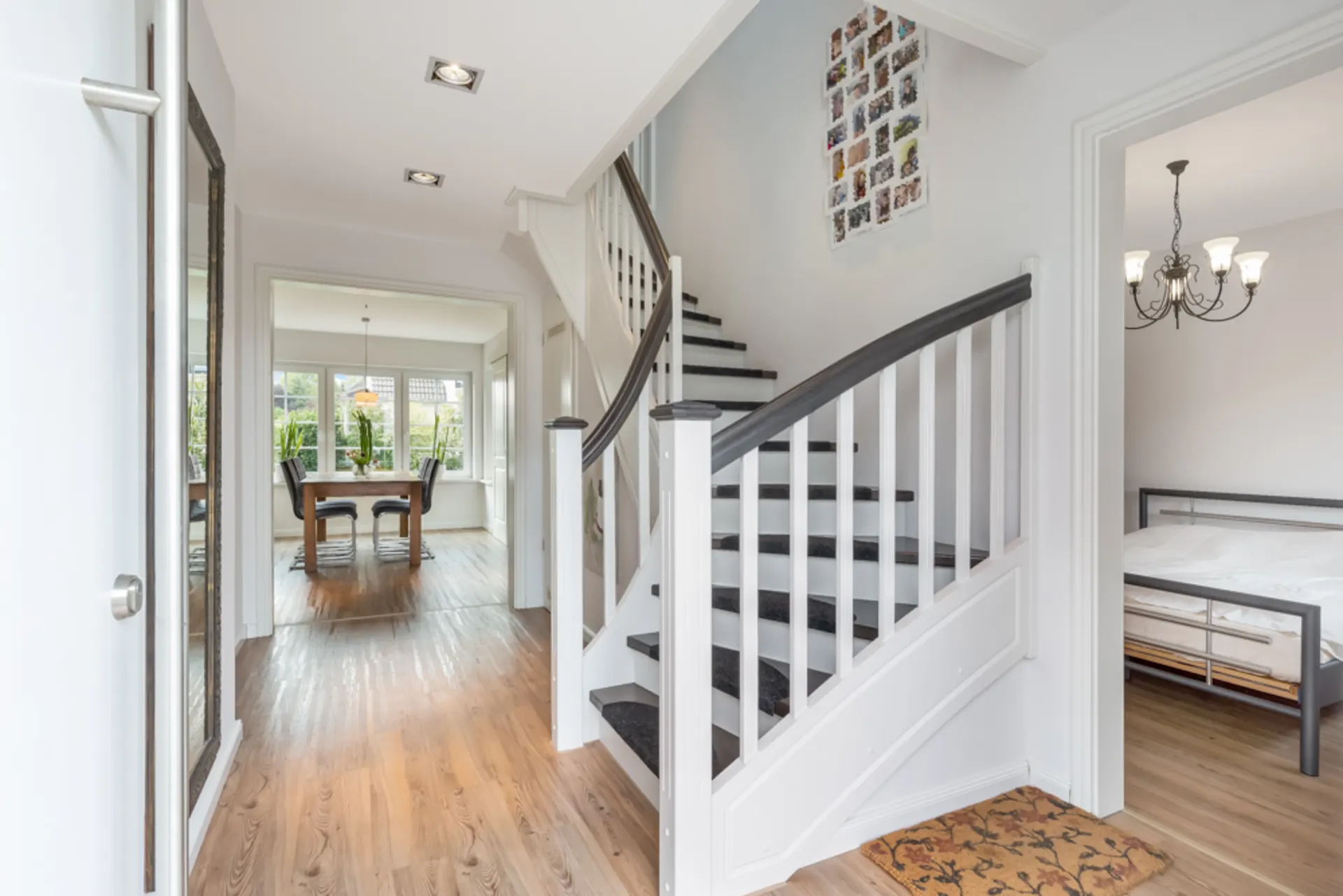 Heller Flur mit Holztreppe, Esszimmer im Hintergrund und Schlafzimmer rechts.
