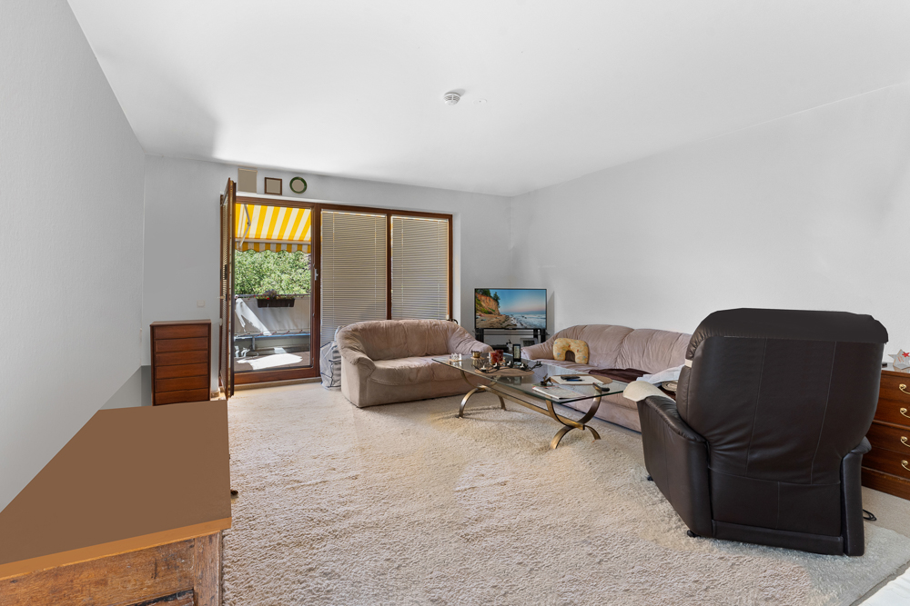 Wohnzimmer mit Sofa, Sessel, Fernseher und Zugang zu einem Balkon mit Markise.
