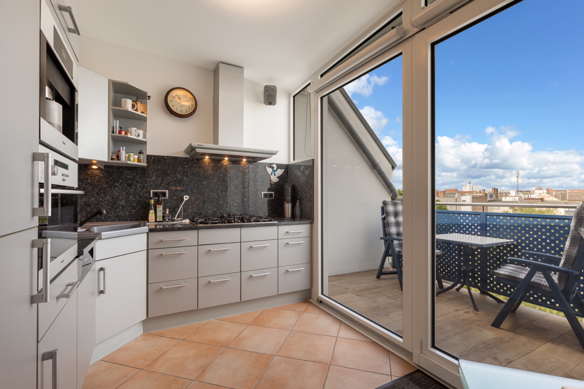 Moderne Küche mit großen Fenstern und Zugang zu einem Balkon mit Sitzecke.