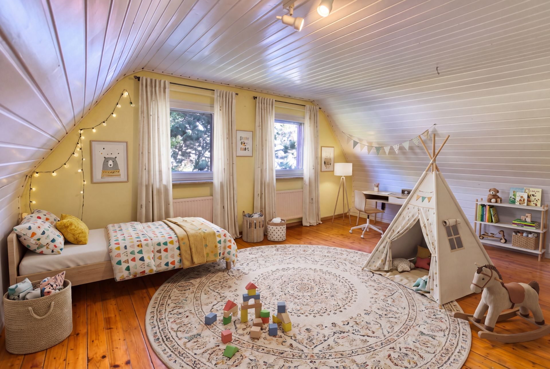 Helles Kinderzimmer mit Bett, Tipi-Zelt, Spielzeug und Teppich auf Holzboden unter Dachschräge.