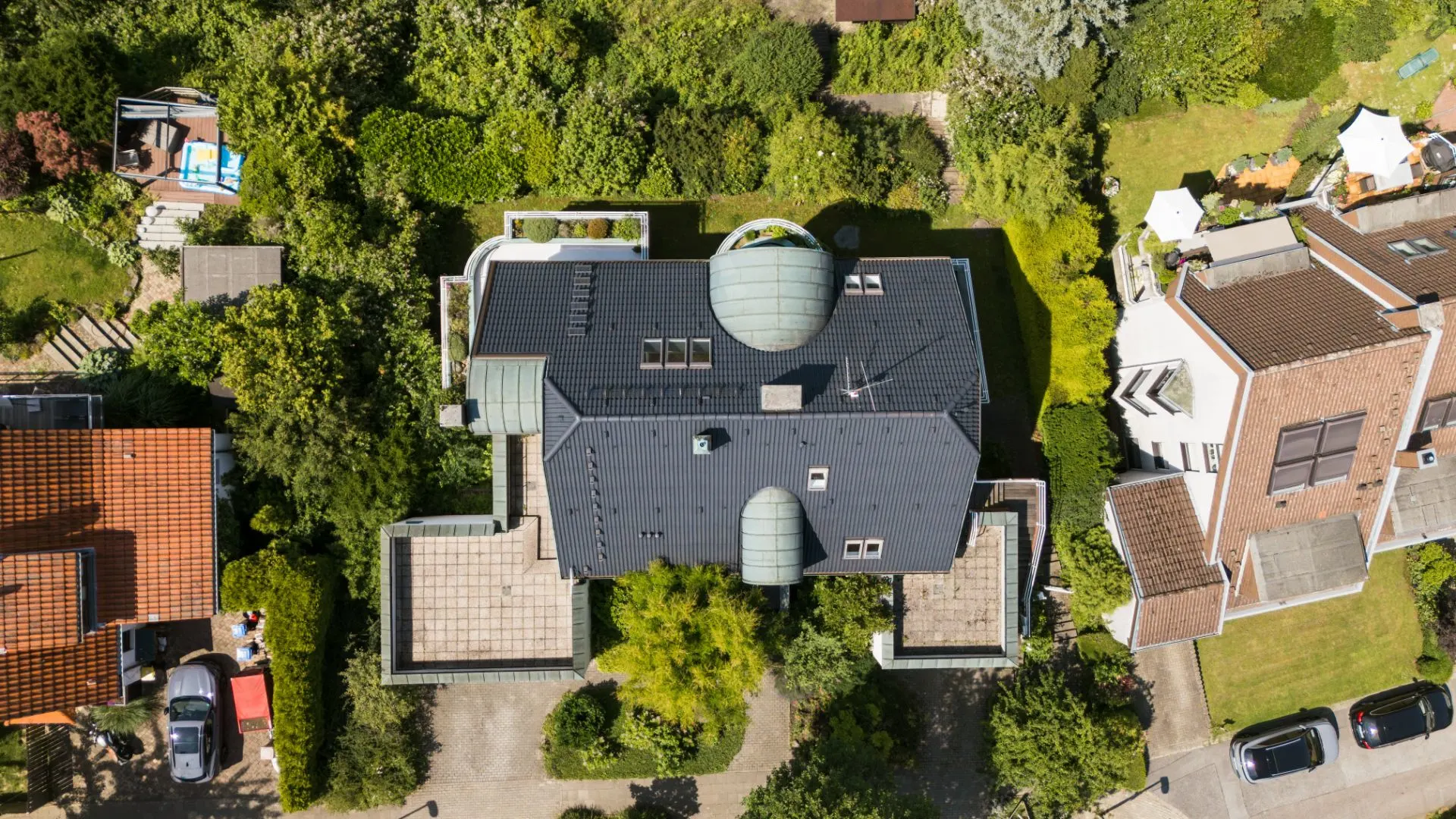 Luftaufnahme eines Wohnhauses mit dunkelgrauem Dach und umliegendem Garten.