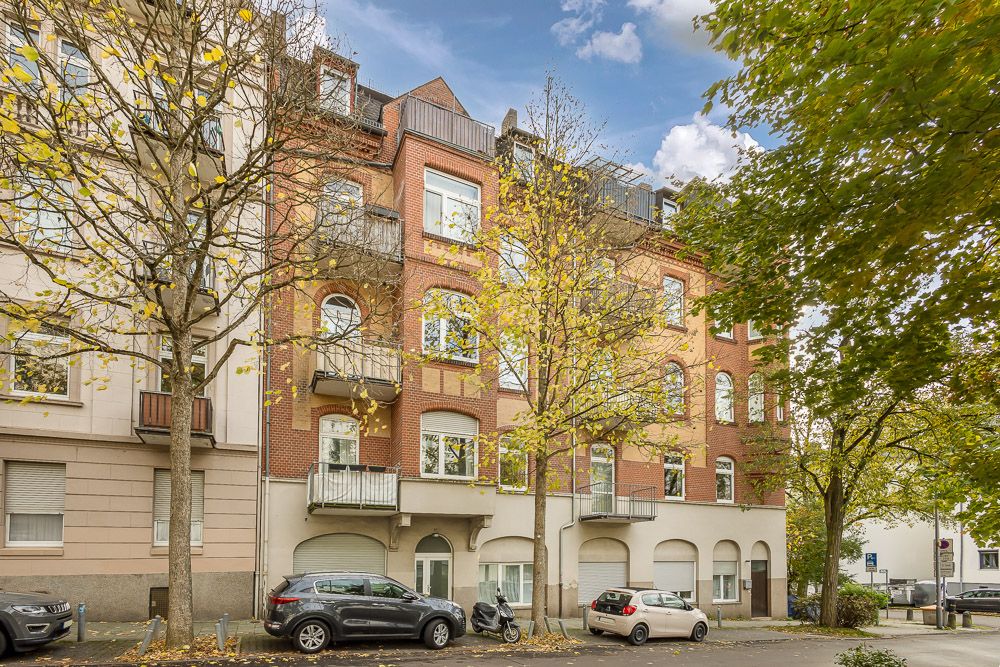 Mehrstöckiges Wohnhaus aus Backstein mit Balkonen und parkenden Autos davor.