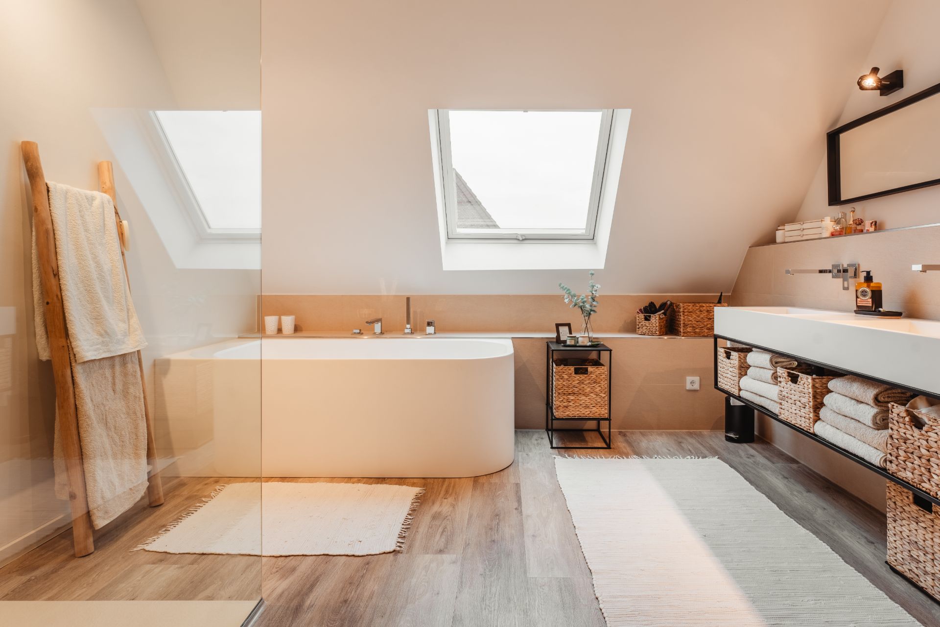 Modernes Badezimmer mit Badewanne, Doppelwaschbecken, Dachfenster und Handtüchern auf Holzleiter.