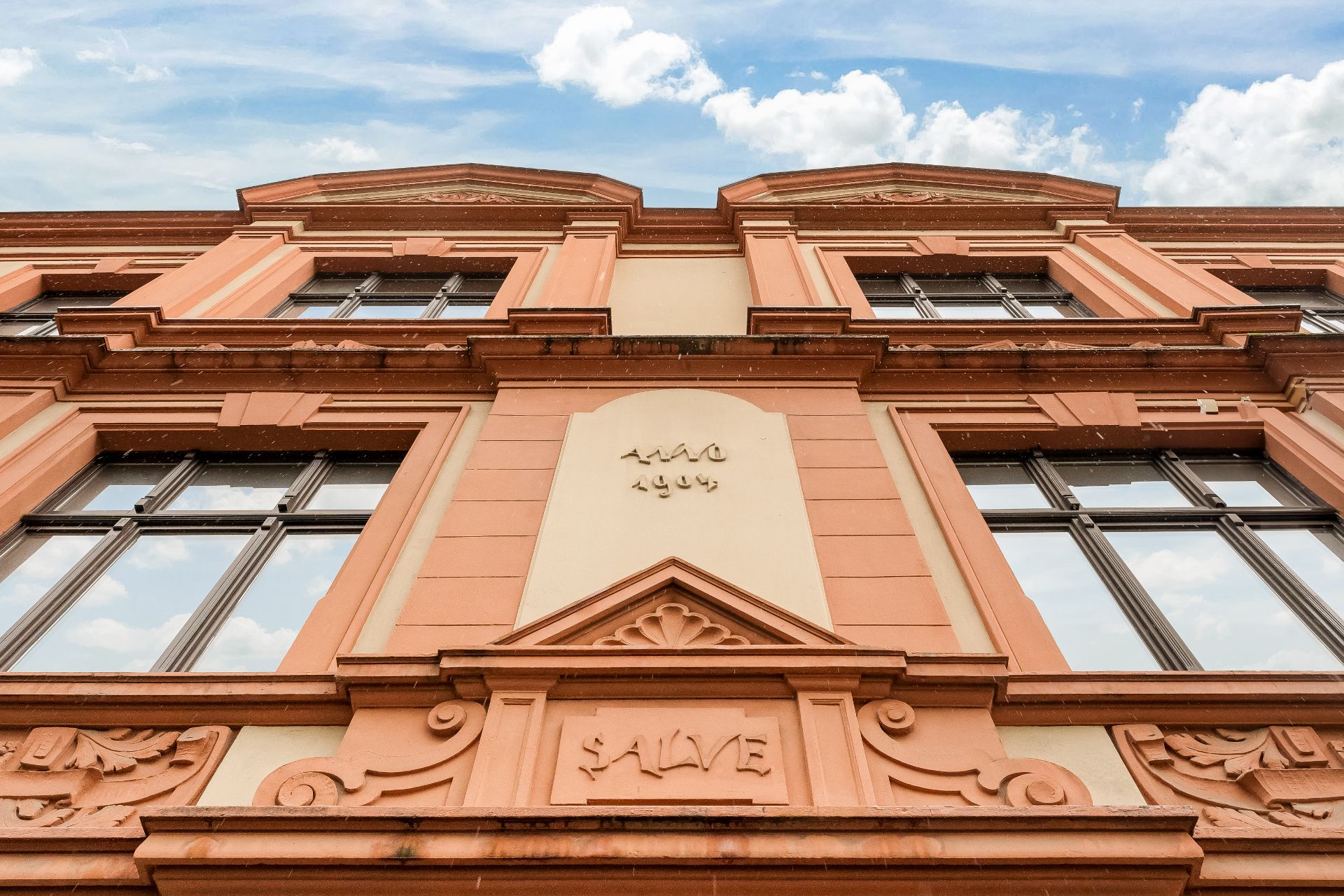 Fassade eines Altbaus mit großen Fenstern und Stuckdetails, Schriftzug SALVE sichtbar.