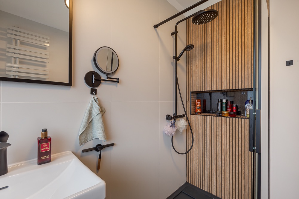Modernes Badezimmer mit Waschbecken und offener Dusche mit Holzwand und Regenduschkopf.