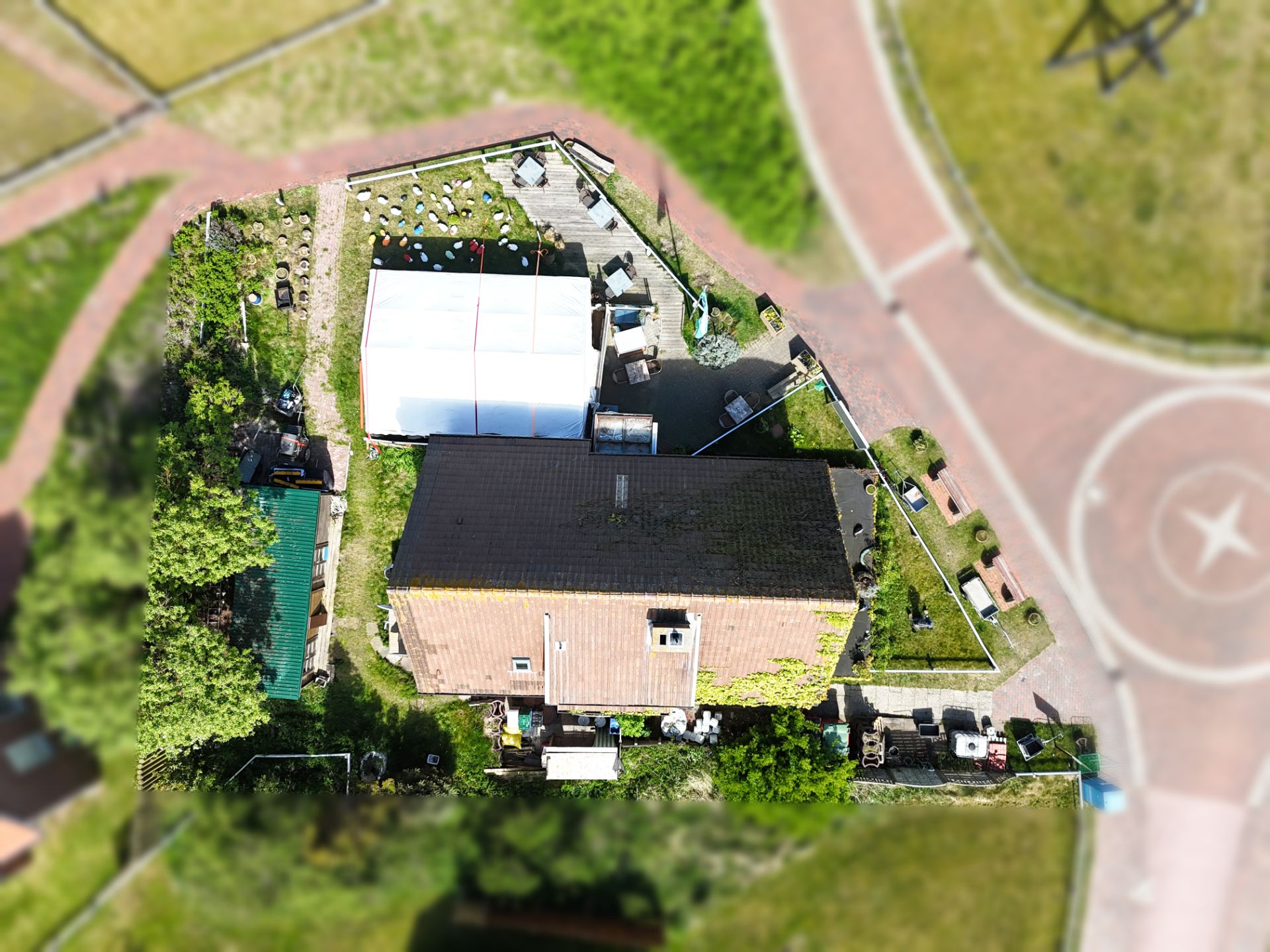 Luftaufnahme eines Wohnhauses mit Garten und Terrasse, umgeben von Gehwegen.
