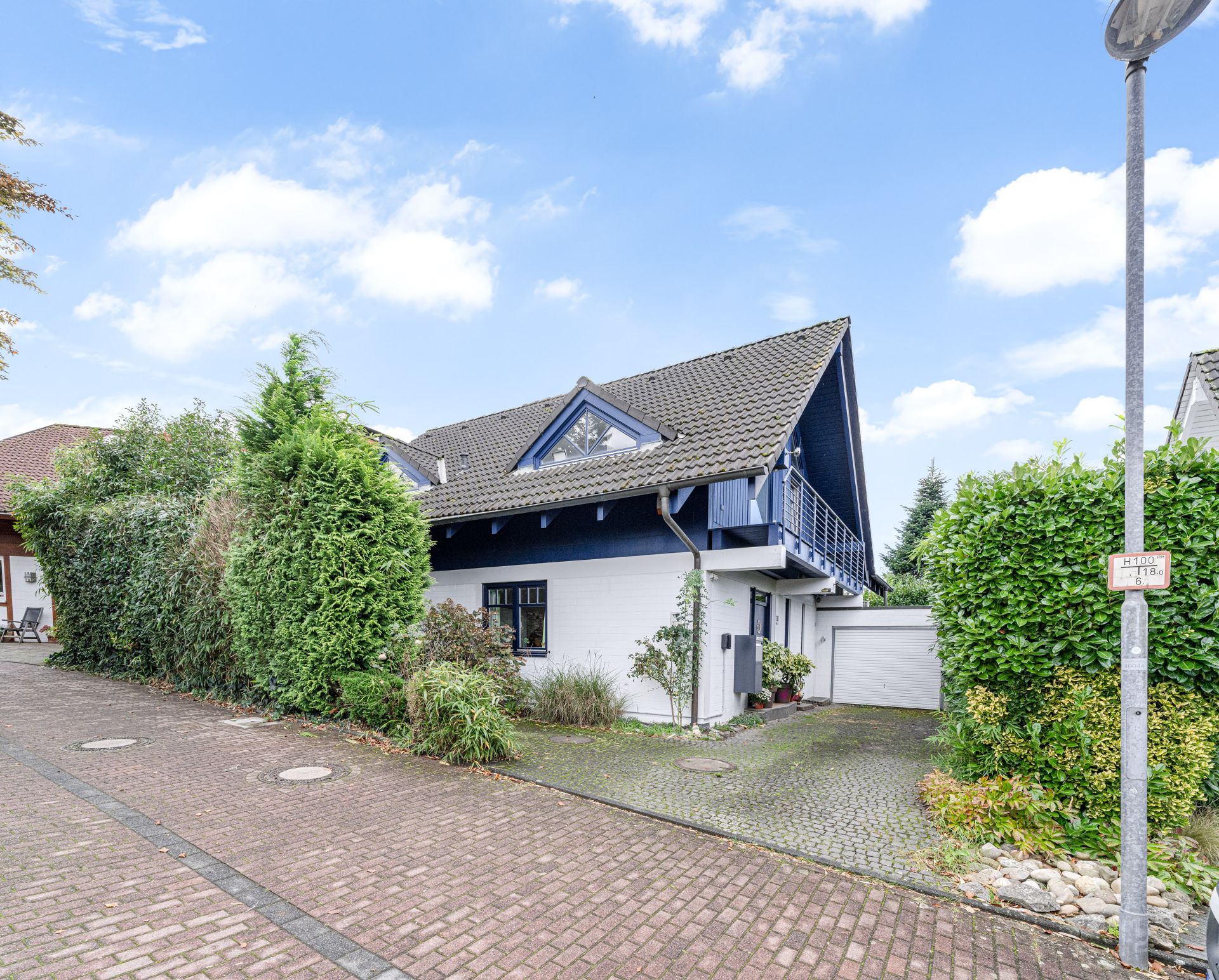 Modernes Einfamilienhaus mit Satteldach, Einfahrt und Garage, umgeben von viel Grün.