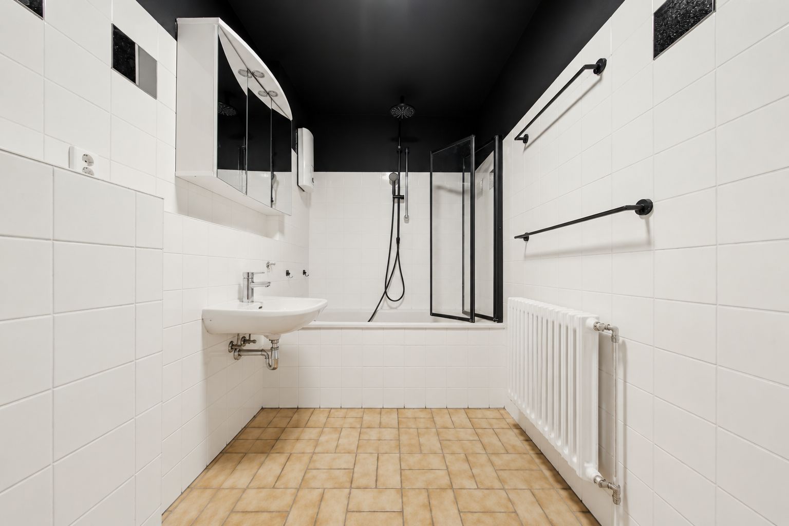 Modernes Badezimmer mit Badewanne, Waschbecken, Spiegel und weißen Fliesen.
