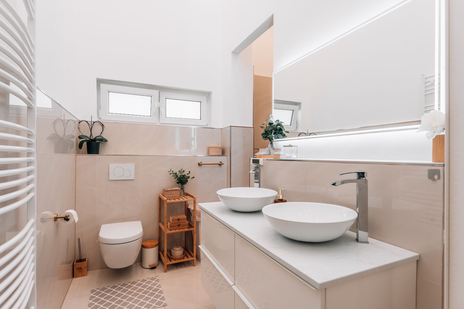 Modernes Badezimmer mit Doppelwaschbecken, Hänge-WC, Spiegel und Dekopflanzen.
