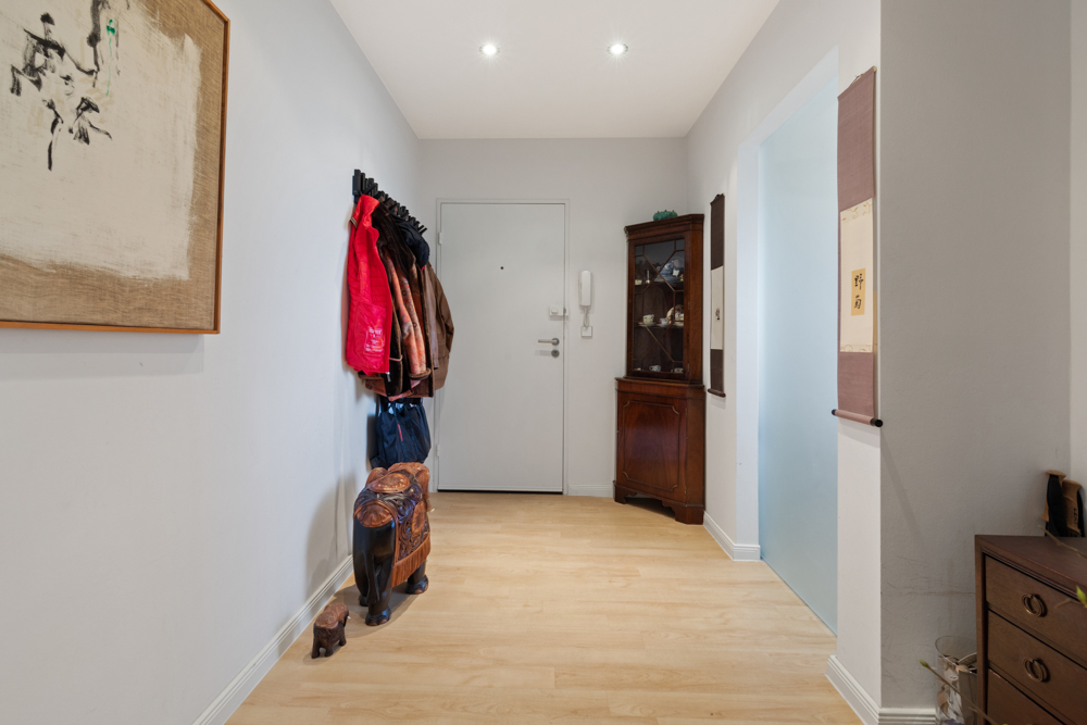 Heller Flur mit Holzschrank, Garderobe, Wandbildern und Dekorationsartikeln.