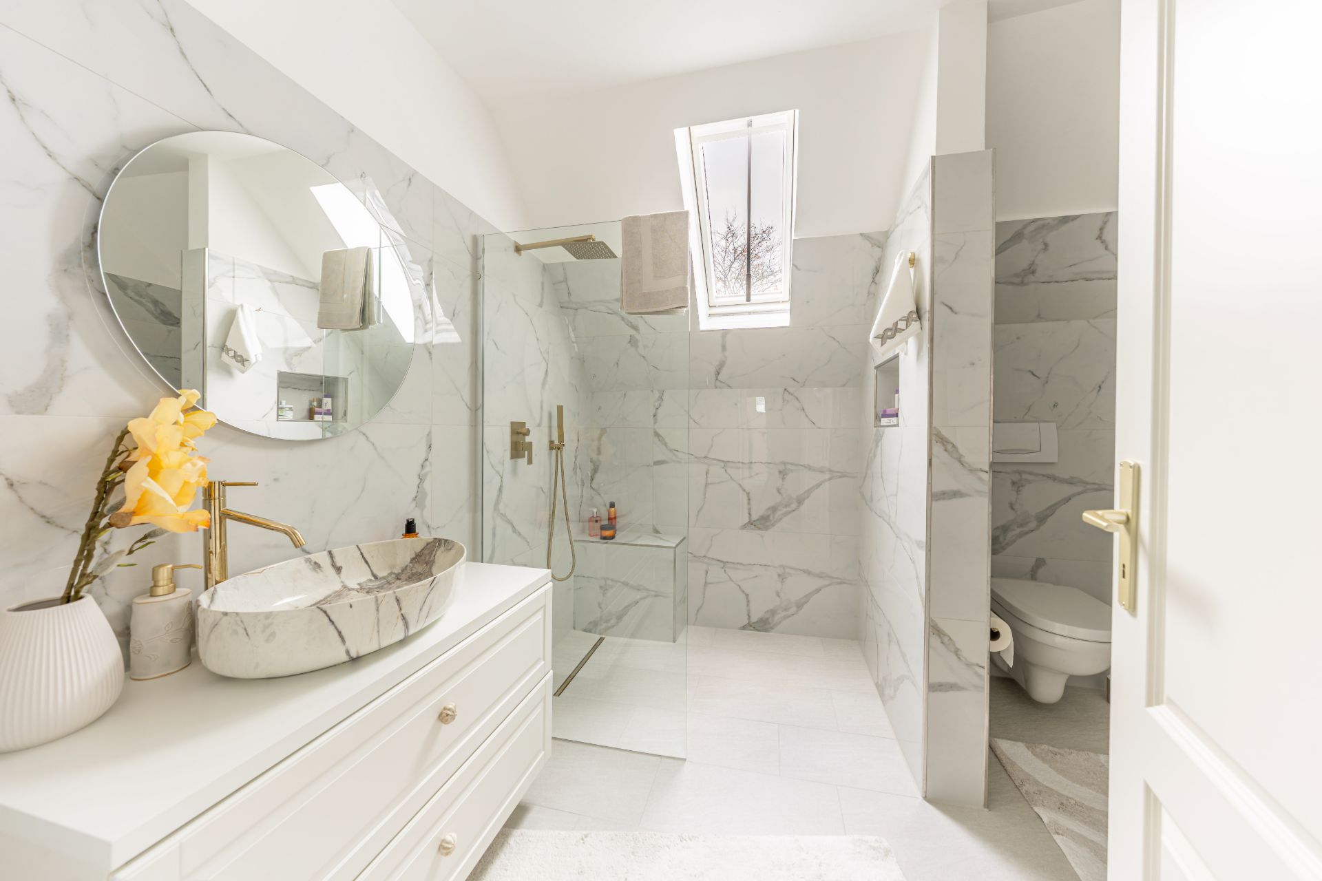 Modernes Badezimmer mit Dusche, Marmorfliesen, rundem Spiegel und Oberlicht.