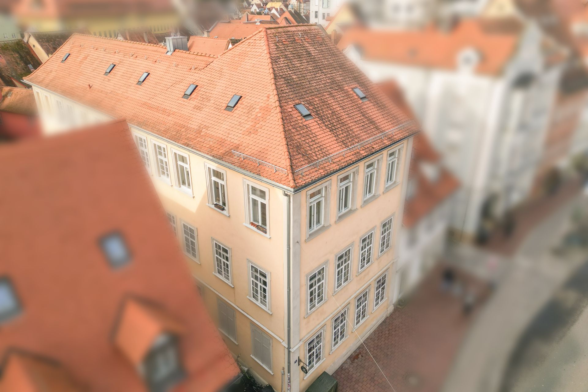 Dreistöckiges, beiges Wohnhaus mit rotem Satteldach und vielen Fenstern.
