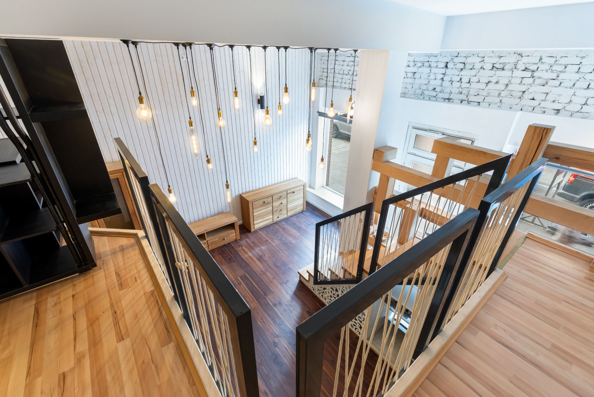 Moderne Wohnzimmertreppe mit Hängelampen, Holzgeländer und großen Fenstern.