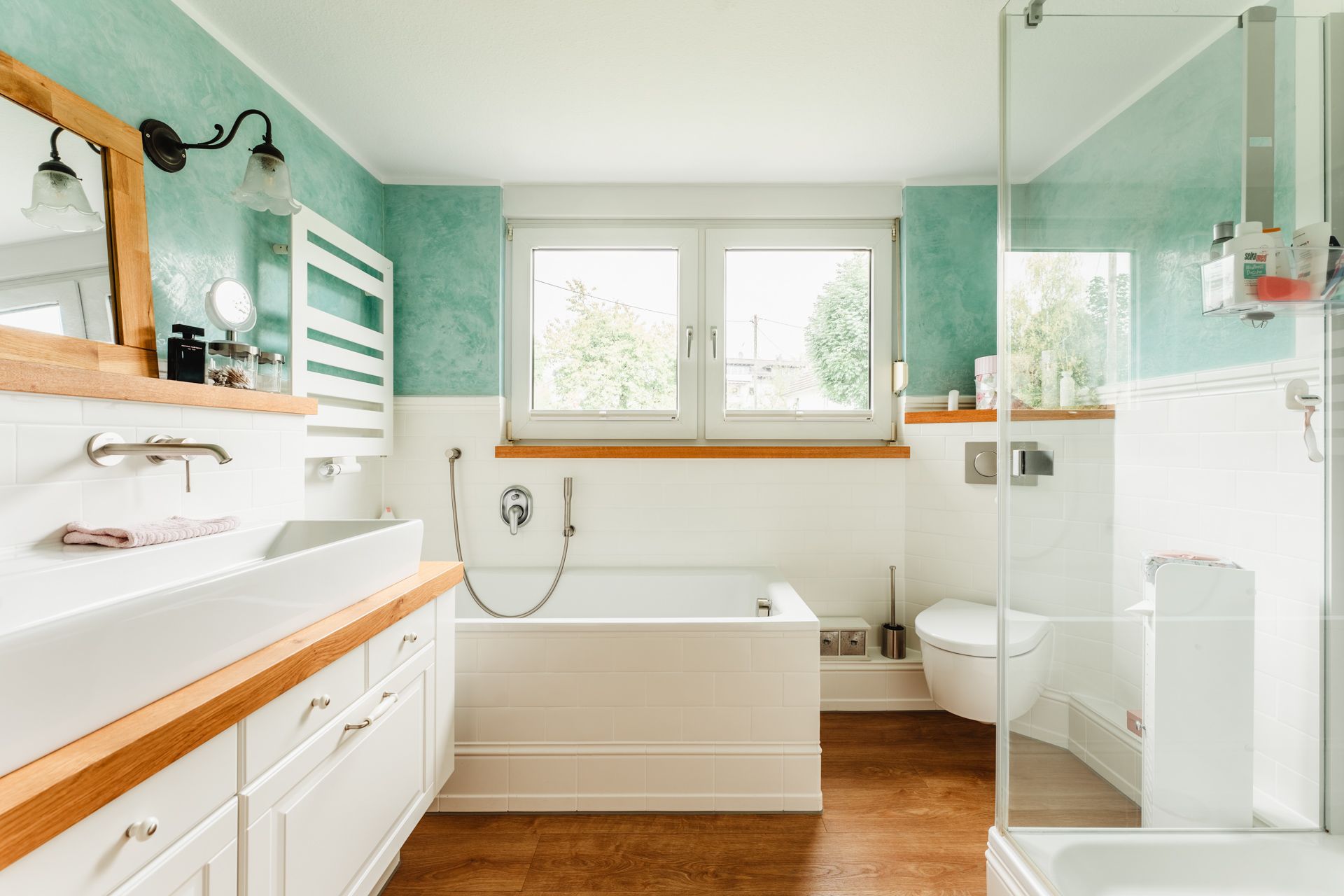 Modernes Badezimmer mit Badewanne, Waschbecken, Toilette und großer Fensterfront.
