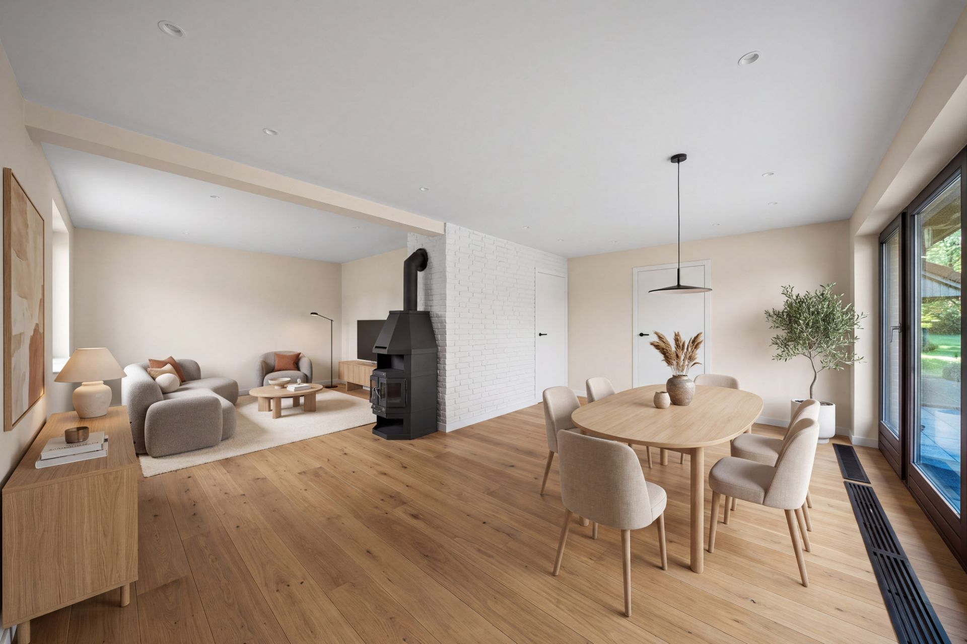 Offenes Wohnzimmer mit Kamin, Essbereich, Holzboden und großen Fenstern mit Blick nach draußen.