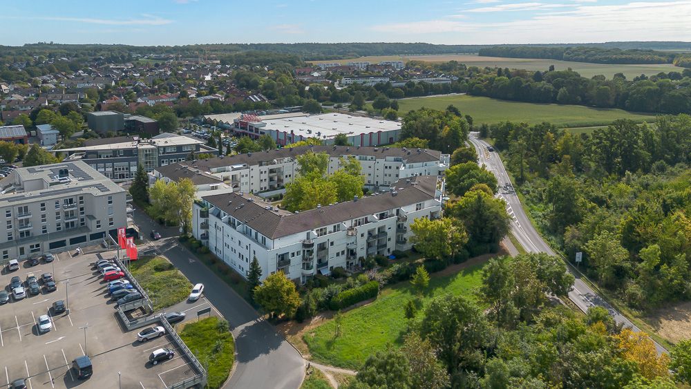 Luftaufnahme eines Wohngebäudekomplexes mit Parkplätzen und umgebender Natur.