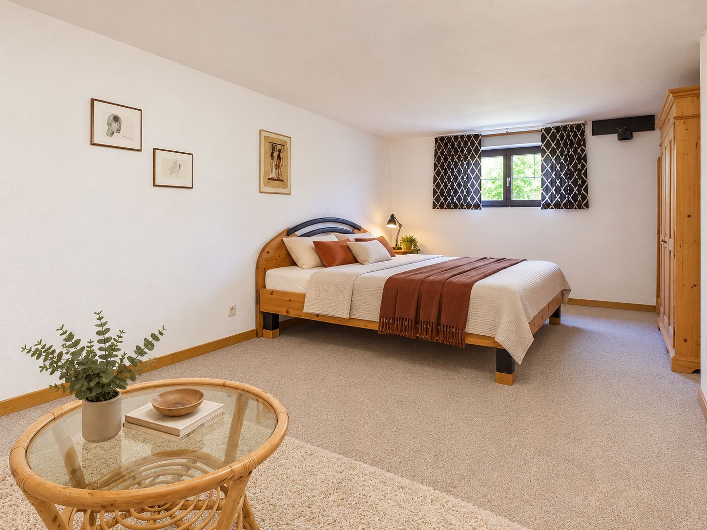 Helles Schlafzimmer mit Doppelbett, Holzmöbeln, Teppich und Fenster mit Vorhängen.