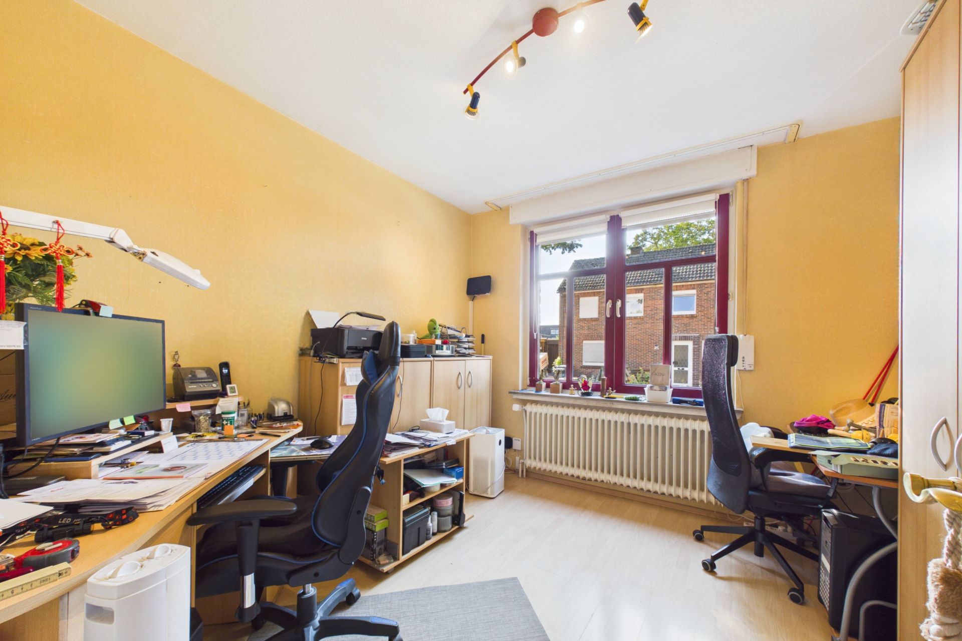 Arbeitszimmer mit zwei Schreibtischen, Stühlen, Computern und großem Fenster mit Blick nach draußen.