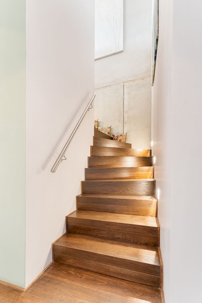 Moderne Holztreppe mit Handlauf und indirekter Beleuchtung an den Wänden.