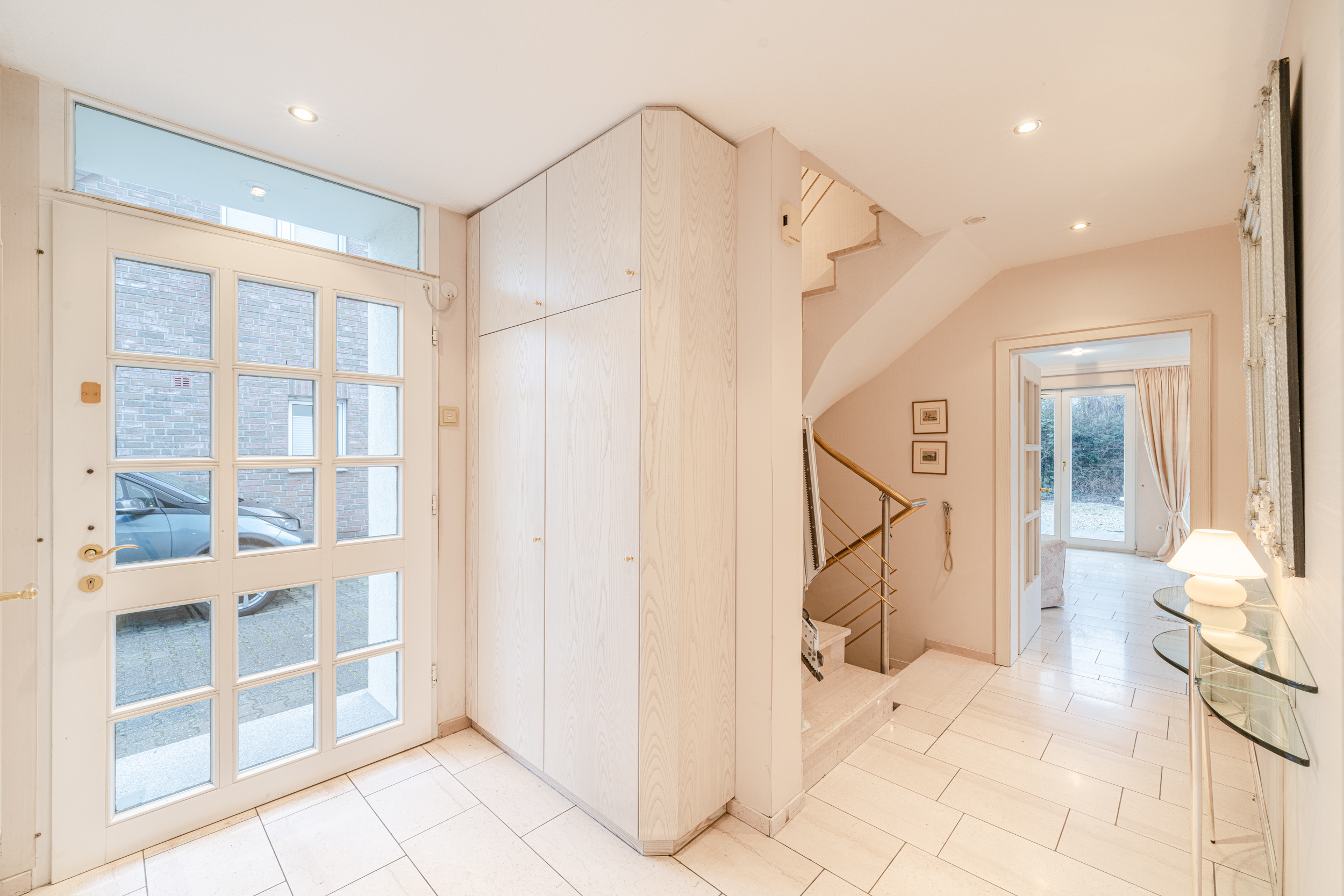Heller Flur mit Glastür, Einbauschrank, Treppe und Zugang zum Wohnzimmer mit Gartentür.