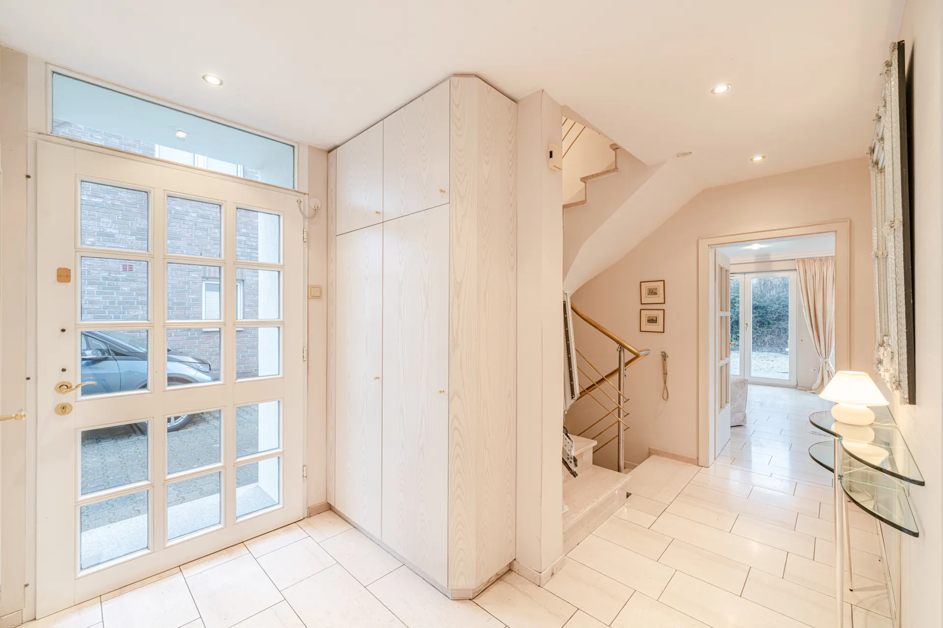 Heller Flur mit Glastür, Einbauschrank, Treppe und Zugang zum Wohnzimmer mit Gartentür.