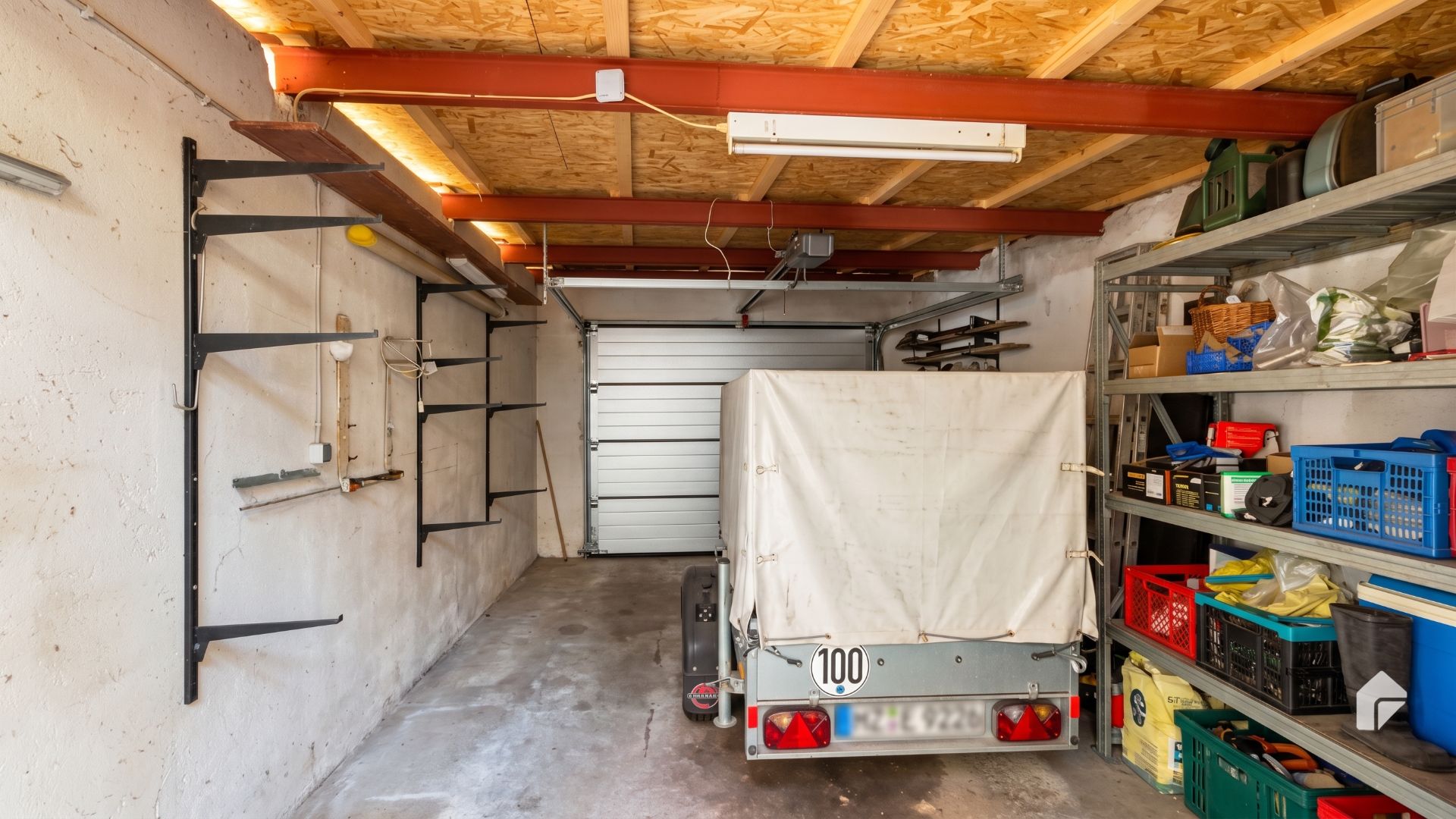 Garage mit Anhänger, Regalen voller Gegenstände rechts und Wandhalterungen links.