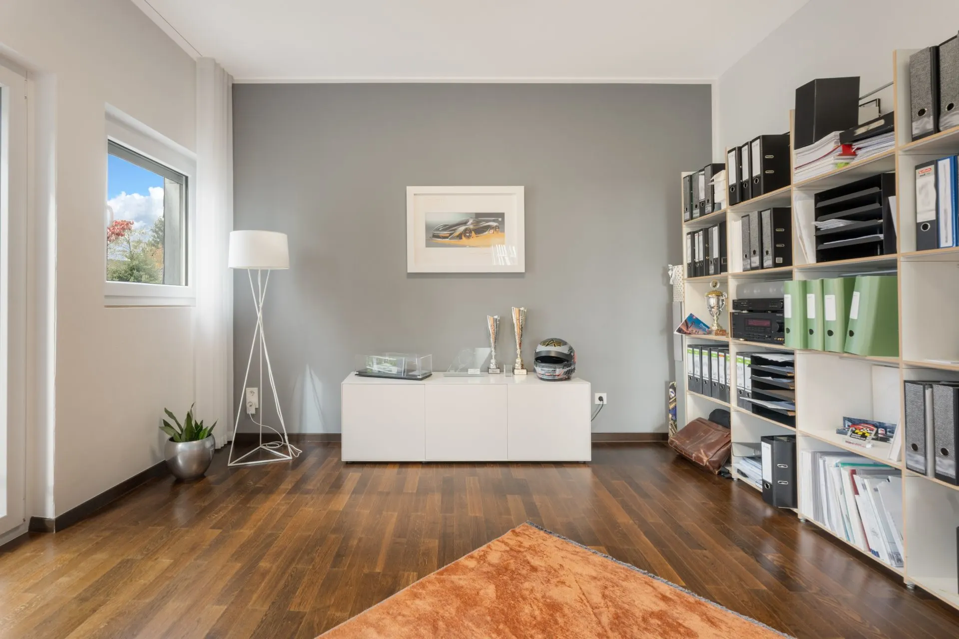 Modernes Arbeitszimmer mit Regal, Schreibtisch, Stehlampe und Bild an der Wand.