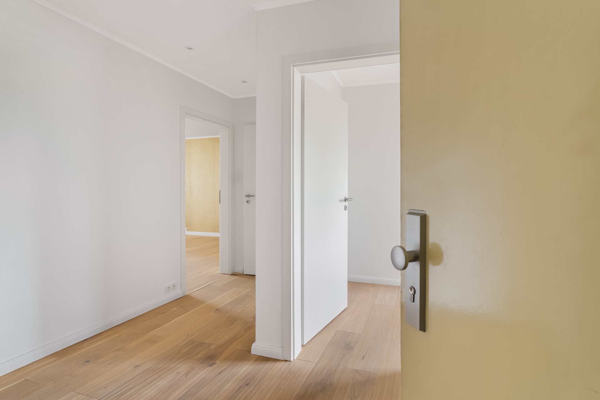 Heller Flur mit Holzboden und mehreren offenen weißen Türen in einer Wohnung.