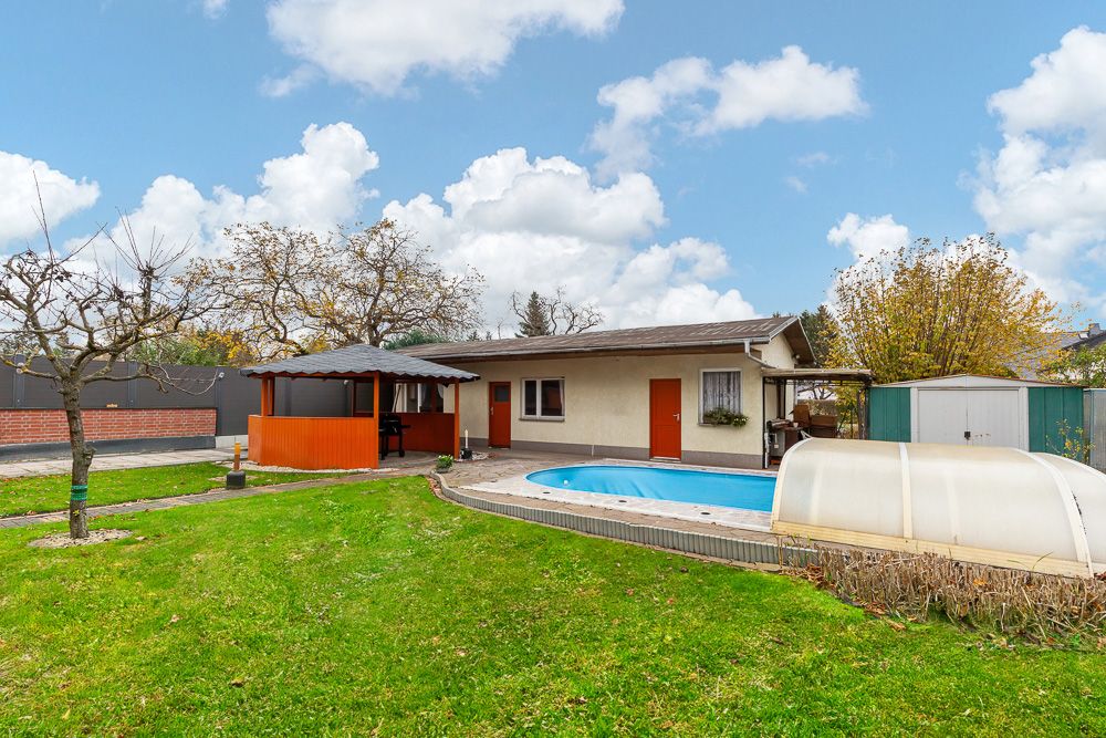 Garten mit Swimmingpool, kleinem Haus, Pavillon und viel grüner Rasenfläche.
