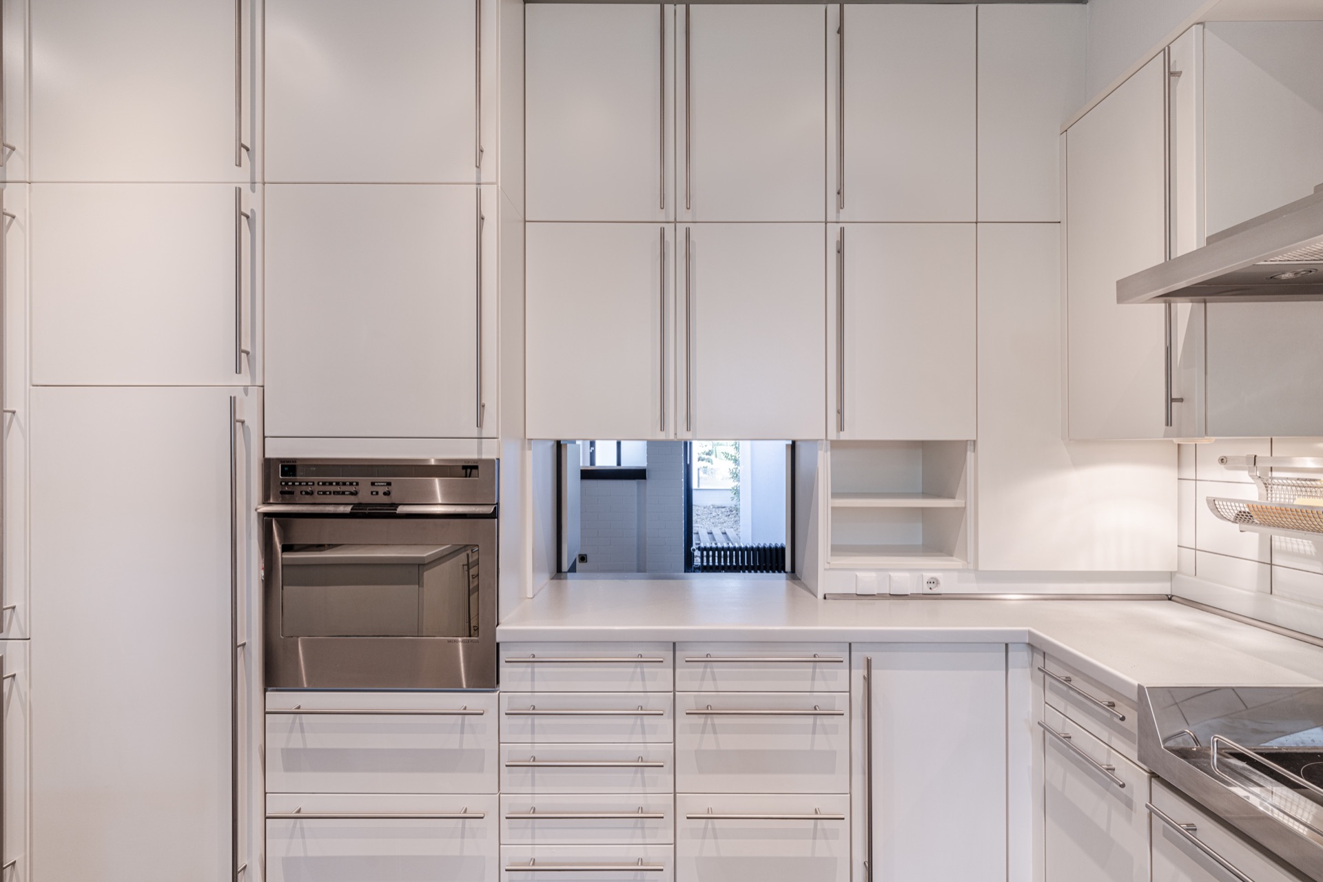 Moderne Einbauküche mit weißen Schränken, Backofen und viel Stauraum.