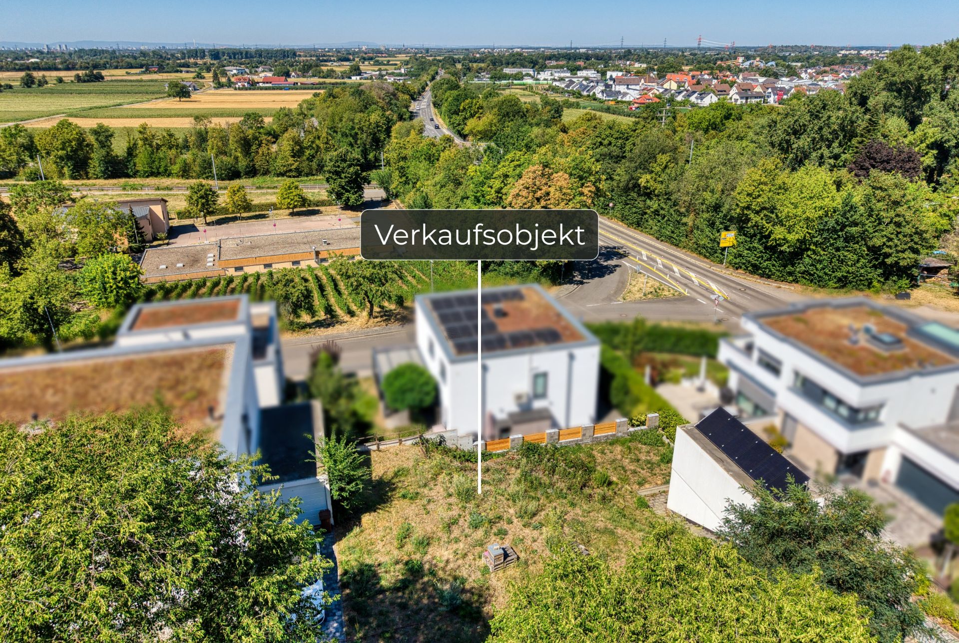 Luftaufnahme von Wohnhäusern, Gärten und einer Landstraße, ein Haus als Verkaufsobjekt markiert.