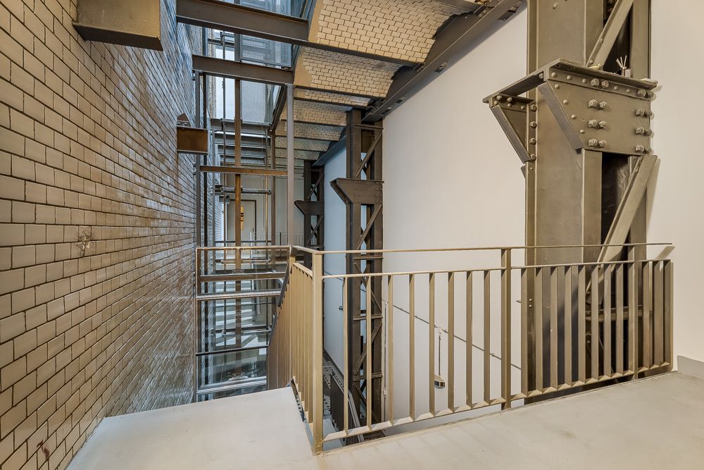 Metalltreppenhaus mit Geländer und freiliegender Stahlkonstruktion in einem Wohngebäude.