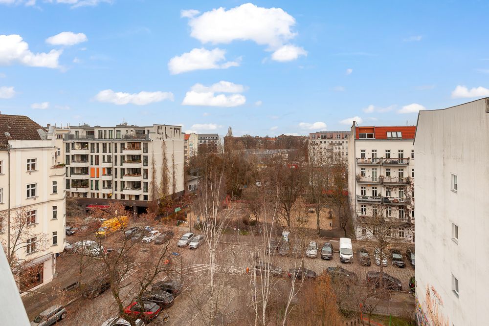 Blick von oben auf einen Wohnhof mit Bäumen, geparkten Autos und umliegenden Wohnhäusern.