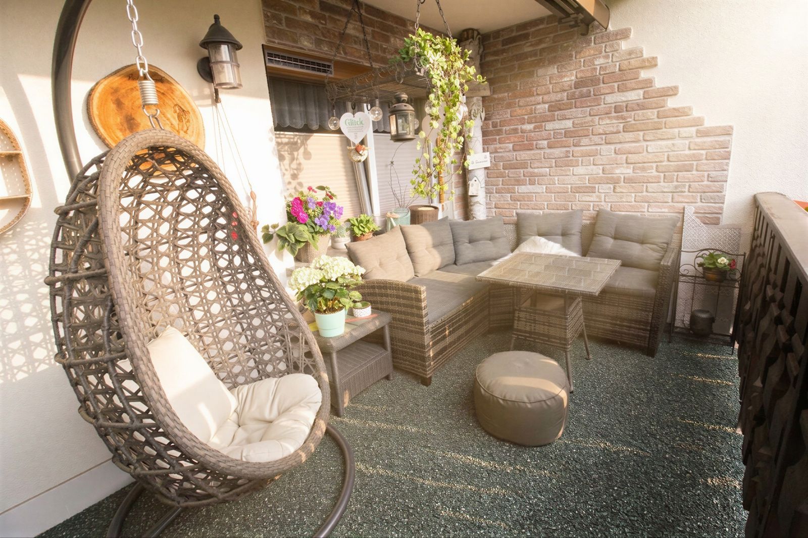 Gemütlicher Balkon mit Hängesessel, Ecksofa, Tisch und vielen Pflanzen.