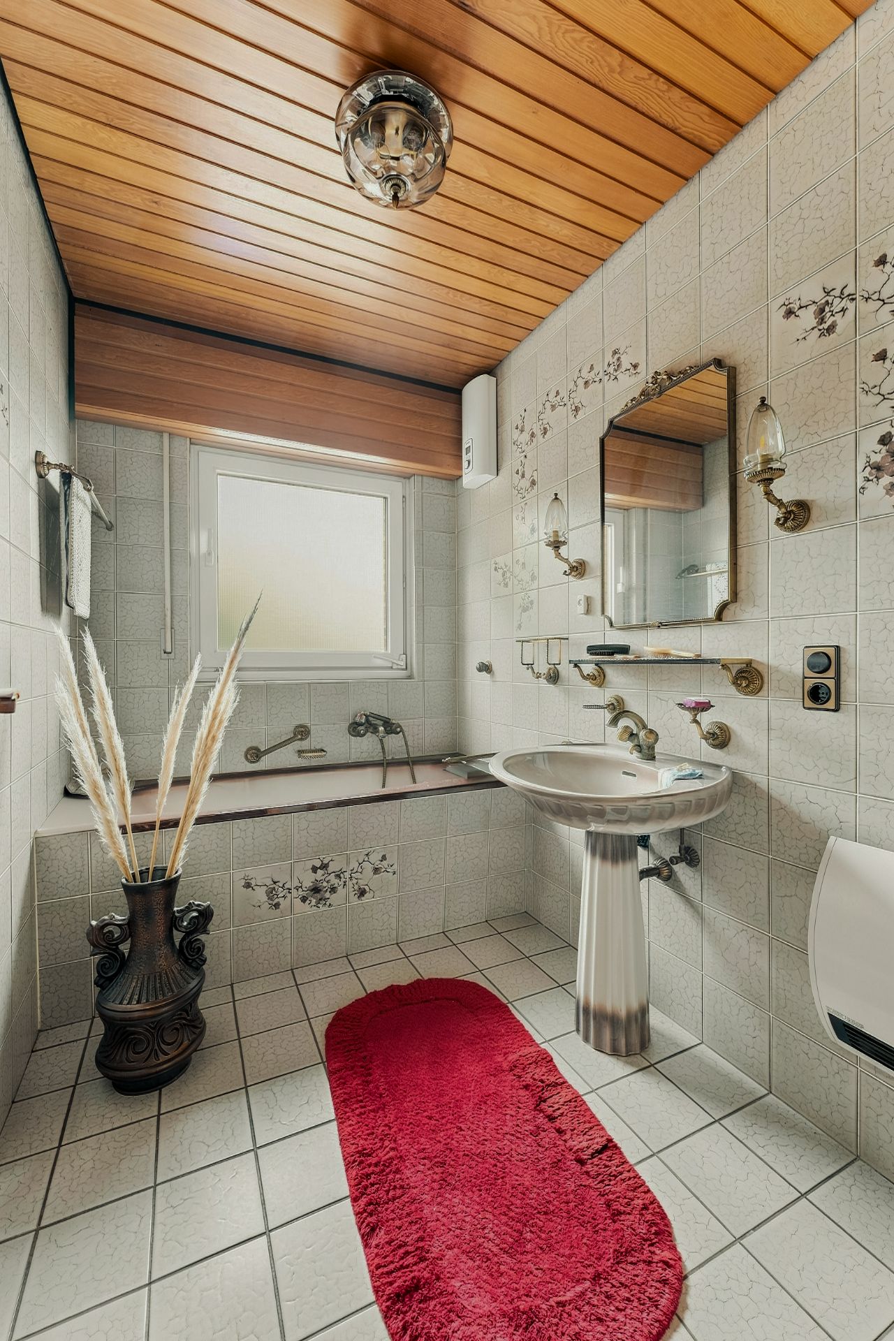 Badezimmer mit Badewanne, Waschbecken, rotem Teppich und Holzdecke.