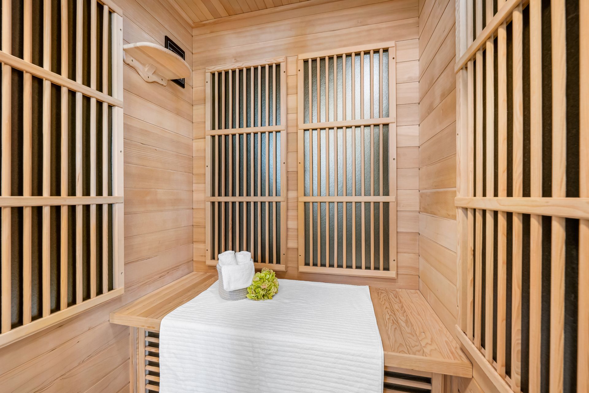 Innenansicht einer privaten Sauna mit Holzverkleidung, Bank und Handtuch.