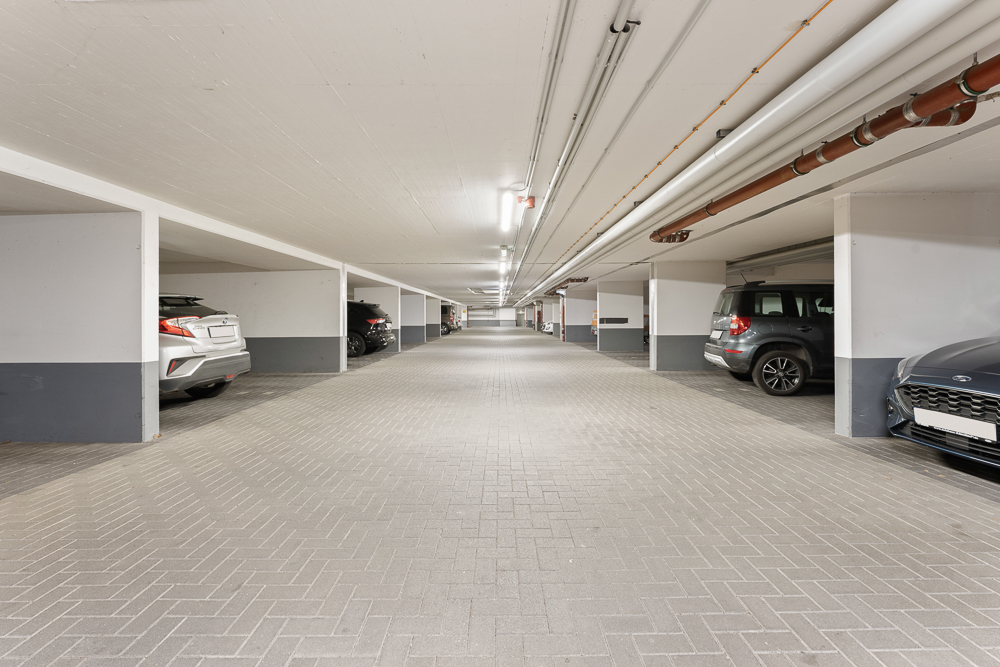 Helle Tiefgarage mit mehreren geparkten Autos in einzelnen Parkbuchten.