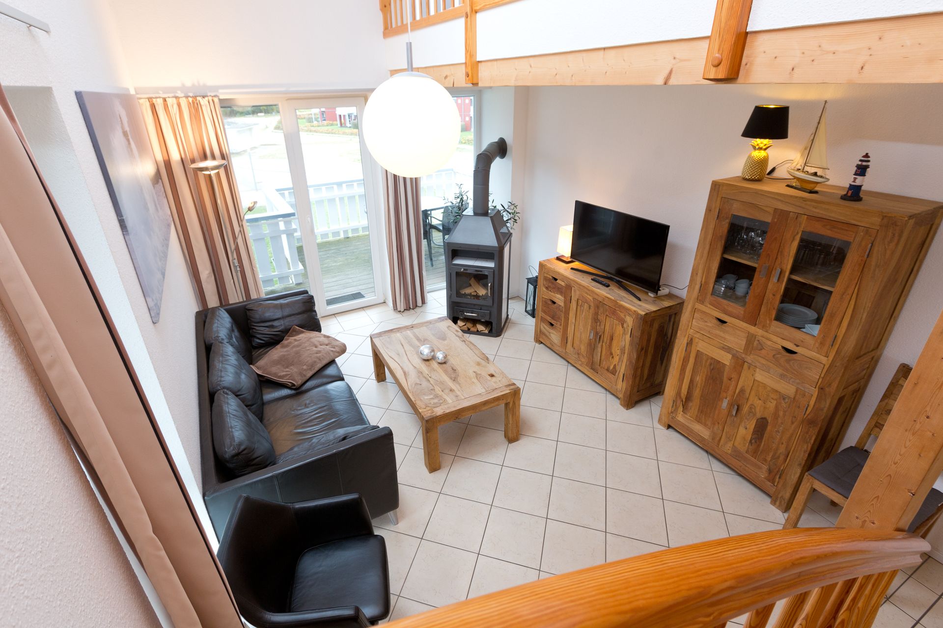 Wohnzimmer mit Ledersofa, Holzofen, Fernseher und Holzmöbeln, Blick von oben.