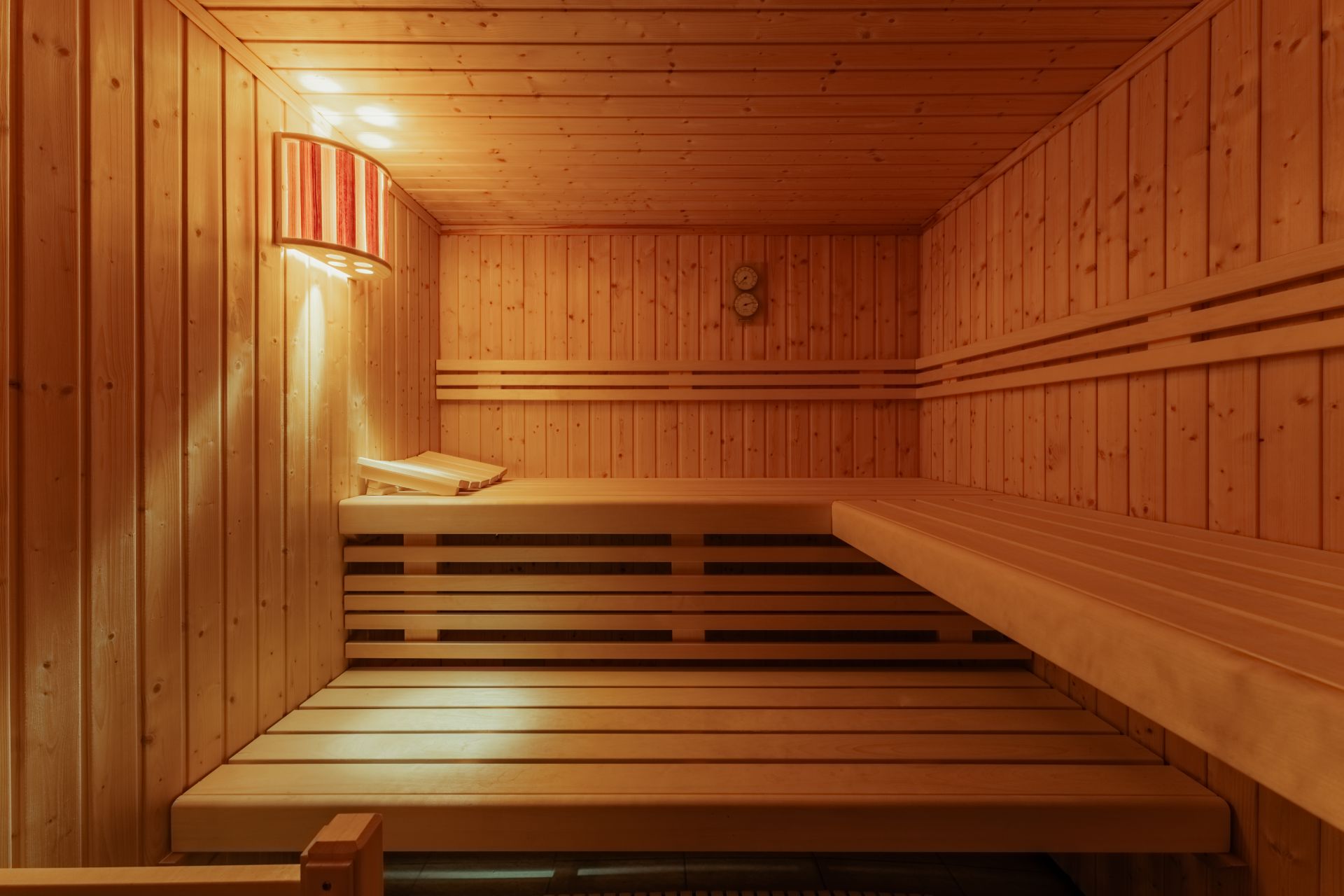 Holzsauna mit zwei Bänken und einem leuchtenden Wandlicht.
