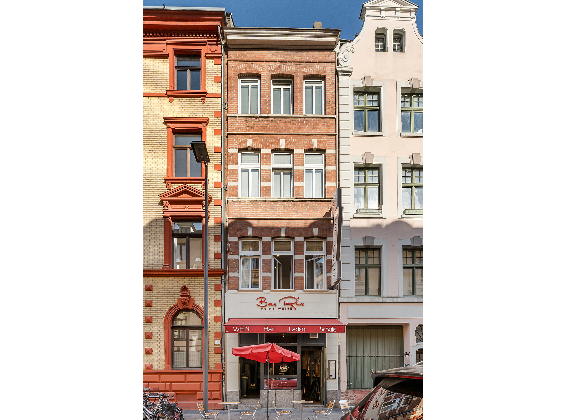 Wohnhaus mit Backsteinfassade, mehreren Fenstern und einem Geschäft im Erdgeschoss.
